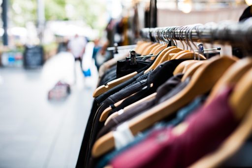Vrouw die kleding bekijkt in een winkel met volle kledingrekken