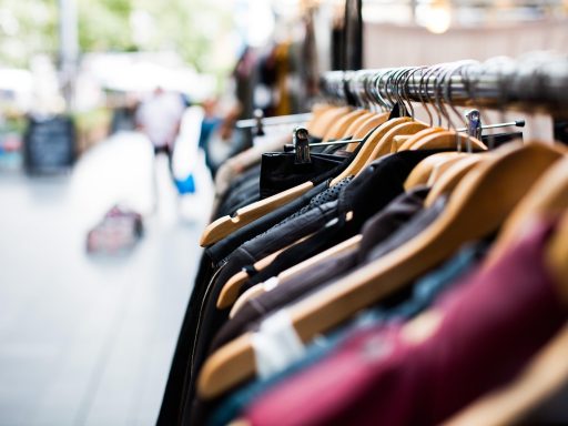 Vrouw die kleding bekijkt in een winkel met volle kledingrekken