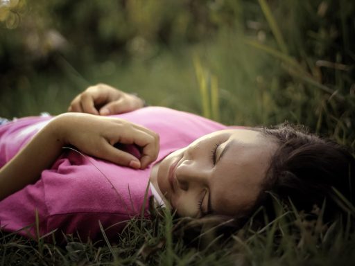 Vrouw ontspant op een ligbed in een groene tuin met kussens en planten rondom